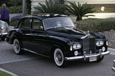 an old black car parked in front of a building