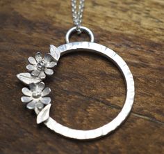 Sterling silver daisy pendant with handmade sterling silver flowers and leaves on a hammered 2.5cm circle. Its an eye-catching, delicate piece of jewellery but more than durable enough for wearing everyday. It would make a lovely gift for yourself or for a loved one. Many thanks for visiting Gray Stokes Jewellery! Affordable Sterling Silver Necklace With Flower Charm, Cheap Sterling Silver Necklace With Flower Charm, Cheap Sterling Silver Necklaces With Flower Charm, Flower Jewelry Indian, Fabric Flower Necklace, Sterling Silver Flower Necklace, Wedding Flower Jewelry, Daisy Pendant, Silver Flower Necklace