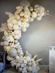 a balloon arch with white balloons and silver ornaments on it in the corner of a living room