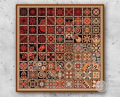 an intricately designed wall hanging on the side of a concrete wall with red and black tiles