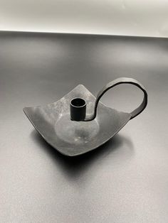 a metal object sitting on top of a black table next to a cup and saucer