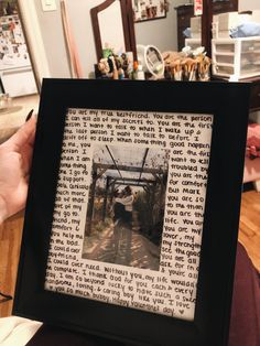 a person holding up a framed photo in front of a table with pictures on it