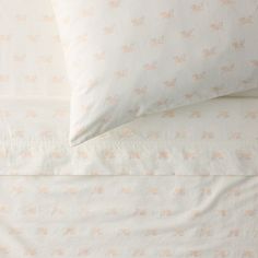 two pillows on top of each other in front of a white bed with pink flowers