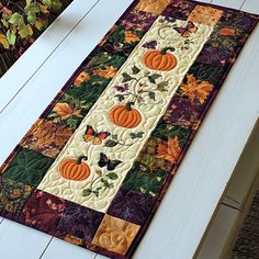 a table runner with pumpkins and leaves on it