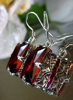 Earrings Description Made to Order This is a brand new beautiful Art Nouveau/Art Deco-inspired filigree sterling silver pair of earrings. The gorgeous 16ctw Simulated Red Ruby are 16mm (5/8th of an inch) by 12mm (1/2 inch) in size dimension. The earrings are marked 925. The earrings are 1 5/16th inches long. Notice the beautiful swirl/heart like craftsmanship of the silver filigree settings. This is a well made beautiful pair of sterling earrings and they are ready to wear. A white gift-box is i Red Filigree Dangle Jewelry, Ornate Red Drop Earrings, Red Dangle Filigree Jewelry, Elegant Garnet Jewelry With Filigree Detail, Elegant Garnet Filigree Jewelry, Elegant Garnet Jewelry With Filigree, Red Intricate Design Jewelry For Gift, Red Jeweled Earrings For Gift, Evening Ruby Dangle Jewelry