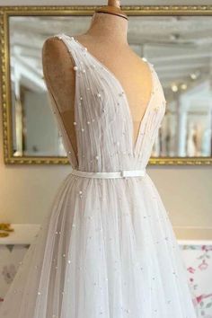 a white wedding dress on a mannequin in front of a mirror