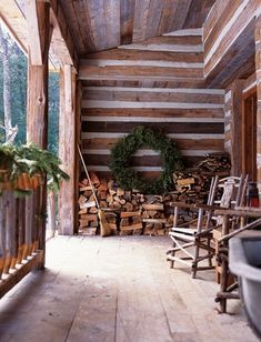 a porch with logs and a wreath on the wall