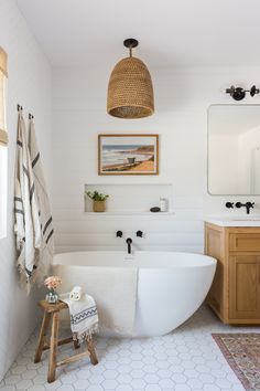 a white bath tub sitting next to a wooden cabinet in a bathroom on top of a tiled floor