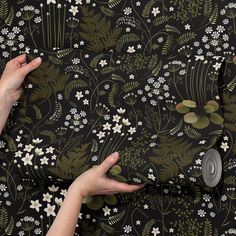 a woman's hands holding onto a black floral wallpaper