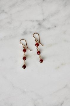 Sweet and dainty, these minimalist gold filled earrings with garnet beads are perfect for everyday wear. The earrings feature tiny faceted pomegranate red garnet beads, dangling from 14k gold filled ear wires.  These cute earrings will look great whether you are heading to a day at work or an evening out. Made using the highest quality USA and UK sourced materials. About Garnet: Garnet has been used as a gemstone for over 5000 years. It has been found in the jewelry of many Egyptian burials and Tiny Gemstone Earrings, Rome Antique, Gemstone Drop Earrings, Gold Dangle Earrings, Garnet Earrings, January Birthstone, Gold Filled Earrings, Red Earrings, Earrings Dainty