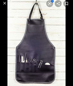 an apron hanging on the wall with scissors and other items in it's pocket