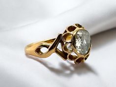 a gold ring with an oval stone in the center on a white cloth, close - up