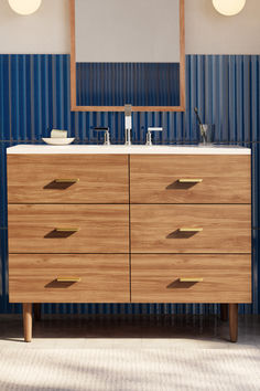 a bathroom vanity with two mirrors and blue striped wallpaper in the backround