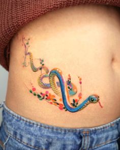 a woman's stomach with a colorful snake tattoo on it