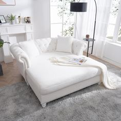 a large white couch sitting on top of a rug in a living room next to a window