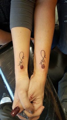 two people holding hands with tattoos on them