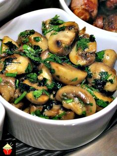 two bowls filled with mushrooms and broccoli on top of a table next to meat