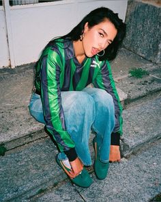 a young woman sitting on the steps with her hand in her mouth and wearing green shoes