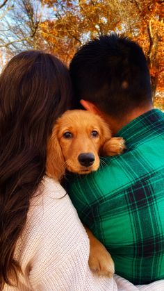 a woman holding a dog in her arms while she is hugging it's head