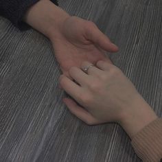 two people holding hands on top of a wooden floor