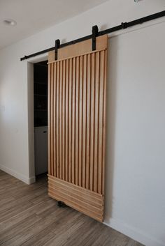 an open sliding door in the corner of a room with hardwood floors and white walls