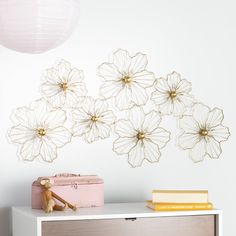 a white dresser topped with a pink chest of drawers next to a wall mounted art piece