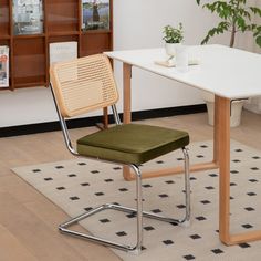 a white table with a green chair next to it and a potted plant on top