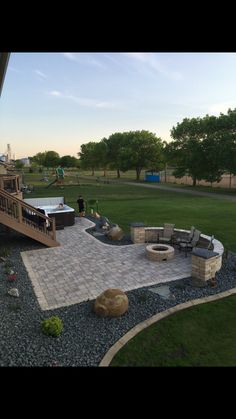 an outdoor patio with fire pit and seating area in the middle of it, surrounded by grass