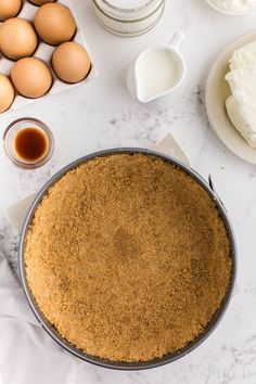 the ingredients to make a pie laid out on a white counter top, including eggs and butter