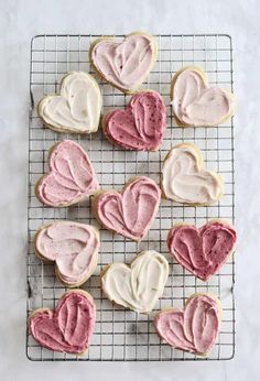 cookies with frosting in the shape of hearts on a cooling rack