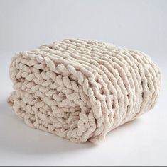 a pile of white knitted blankets sitting on top of a white floor next to each other