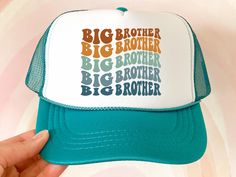 a person holding up a trucker hat with the words big brother written on it