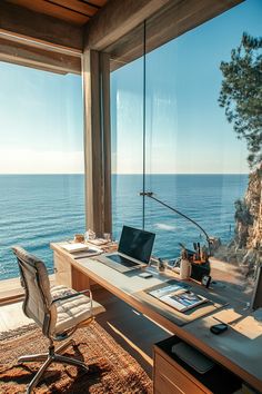 a desk with a laptop on it in front of a large window overlooking the ocean