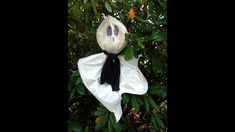 a stuffed ghost hanging from a tree with leaves around it's neck and eyes