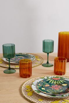 a table topped with plates and glasses on top of a wooden table covered in glassware