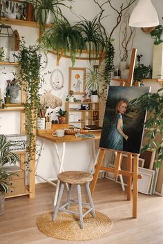 an artist's studio with plants and paintings