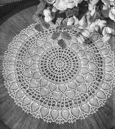 a white doily sitting on top of a wooden table next to flowers and leaves