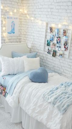 a bedroom with white brick walls and light blue bedding, pillows and pictures on the wall