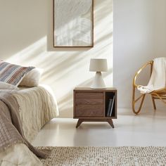 a bed room with a neatly made bed next to a night stand and a chair