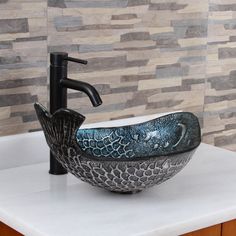 a bathroom sink with a black faucet on top of it next to a tiled wall