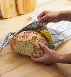 a person holding a loaf of bread on top of a wooden table