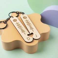 two personalized wooden keychains sitting on top of each other in front of a colorful background