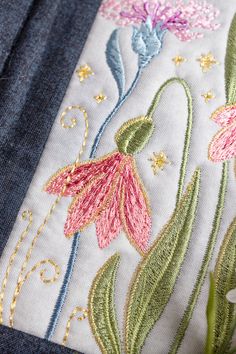 a close up of a piece of cloth with flowers on it and gold threading