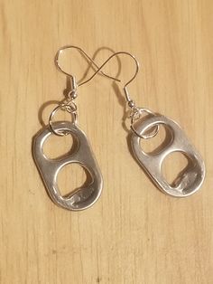 pair of silver earrings sitting on top of a wooden table