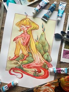 some art supplies are laying out on the table and there is a drawing of a mermaid