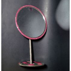 a mirror that is sitting on top of a metal stand with pink beads around it