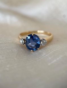 a blue sapphire and diamond ring on a white cloth