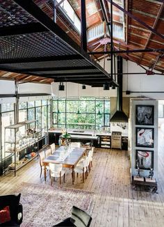 an open kitchen and dining room with wood flooring, exposed ceilings and large windows