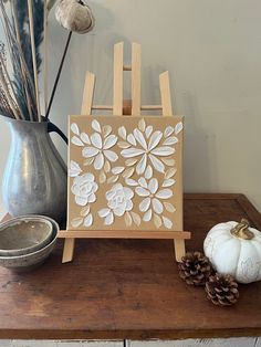 a wooden easel sitting on top of a table next to a vase with flowers