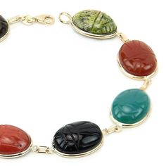 14k yellow gold gemstone scarab bracelet featuring 12 X 16 mm unikite, red jasper, black onyx, blue lace agate, blue onyx, carnelian, green onyx and tiger eye. Egyptian style scarab gemstones are hand set into 14K gold bezels and are connected to each other with 14K gold links. Details Length: 7 - 8.5 Inches Stone Size: Oval 16 X 12 mm Metal Type: 14K Gold Type Of Lock: Lobster Lock Fine Jewelry Bracelet With Cabochon, Yellow Gold Oval Agate Jewelry, Oval Agate Yellow Gold Jewelry, Oval Yellow Gold Agate Jewelry, Oval Multicolor Jewelry For Formal Occasions, Oval Cabochon Bracelet In Fine Jewelry Style, Oval Cabochon Bracelets Fine Jewelry, Fine Jewelry Cabochon Bracelets As Gift, Oval Cabochon Bracelet Fine Jewelry